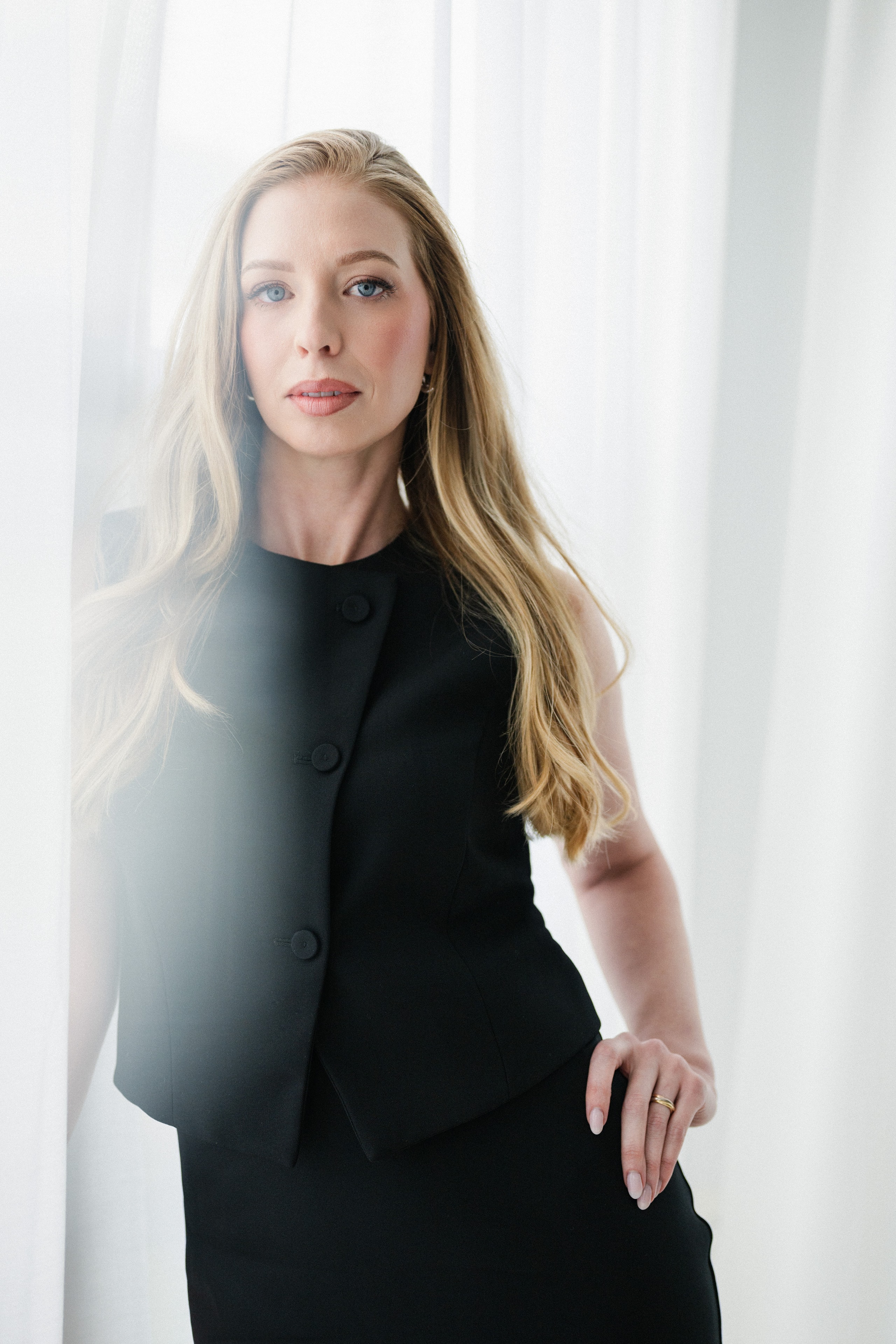 Portrait — black vest, white curtains